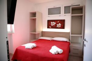 a bedroom with a red bed with two towels at BlueBay Residence Resort in Taranto