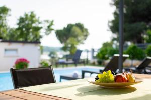 a plate of fruit on a table near a pool at Stancia Rosa - apartment Kiwi in Poreč