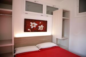 Un dormitorio con una cama roja con una pintura en la pared en BlueBay Residence Resort, en Taranto