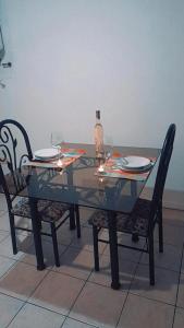 a glass table with two chairs and a bottle of wine at Departamentos Parque Benegas in Godoy Cruz
