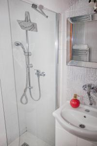 a white bathroom with a shower and a sink at Contact Apartman in Bardejov