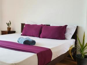 uma cama com almofadas roxas e brancas em Hoxton Bay Surf House weligama em Weligama