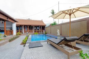 a pool with chairs and an umbrella next to a house at Arshaka Villa in Amed