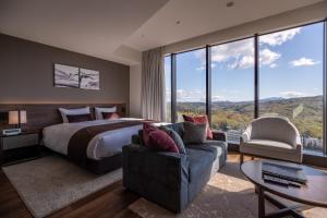 Habitación de hotel con cama, sofá y ventanas en The Vale Rusutsu en Rusutsu