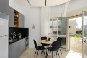una cucina e una sala da pranzo con tavolo e sedie di Bauhaus 2BR with Sea View & Balcony by FeelHome a Tel Aviv