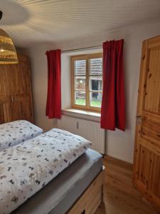 a bedroom with a bed and a window with red curtains at Sonnseitn FW in Bad Heilbrunn