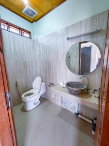 ein Badezimmer mit einem WC, einem Waschbecken und einem Spiegel in der Unterkunft Lara Homestay in Kuta Lombok