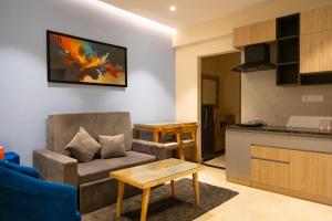 a living room with a couch and a kitchen at Palm Regal Resort in Gopālpur