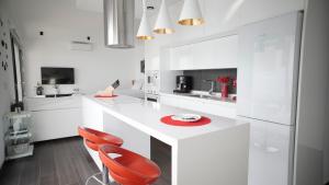 een witte keuken met rode stoelen en een aanrecht bij VILLA ANYWAY CONIL Un lujo frente al mar in Conil de la Frontera