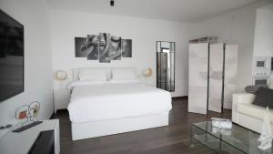 een witte slaapkamer met een wit bed en een bank bij VILLA ANYWAY CONIL Un lujo frente al mar in Conil de la Frontera +61 foto's