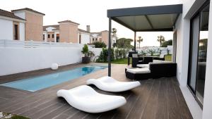 een patio met witte stoelen en een zwembad bij VILLA ANYWAY CONIL Un lujo frente al mar in Conil de la Frontera