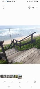 a wooden bench sitting on a boardwalk near the beach at Coastal Cottage in Klein Brak Rivier +9 photos