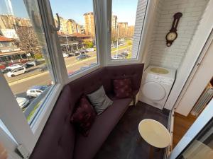 um sofá num pequeno quarto com duas janelas em Hedonic Studio em Belgrado