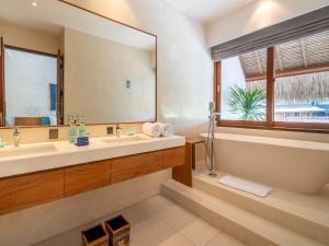 a bathroom with a sink and a large mirror at IZE Canggu by LifestyleRetreats in Canggu
