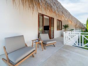 a patio with two chairs and a thatch roof at IZE Canggu by LifestyleRetreats in Canggu