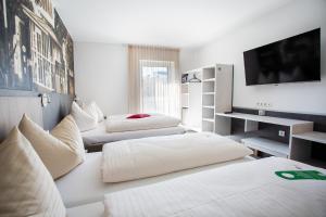 two beds in a room with a tv and a room with at FairSleep AVIA Motel Zwettl in Zwettl Stadt