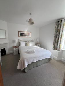 a white bedroom with a large bed and a fireplace at Bay View Guest House in Beer