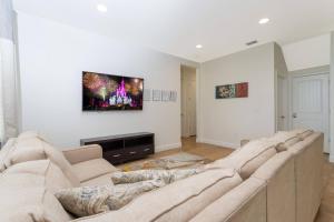 sala de estar con sofá grande y TV en la pared en Top Villas - Encore Resort 1528, en Orlando