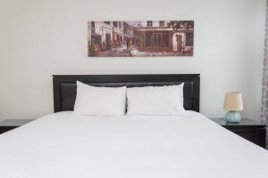 ein Schlafzimmer mit einem weißen Bett und einem Gemälde an der Wand in der Unterkunft Top Villas - Encore Resort 1528 in Orlando
