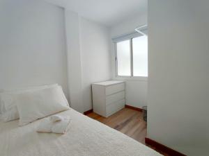 ein weißes Schlafzimmer mit einem Bett und einem Fenster in der Unterkunft Pozo Wave Properties in Pozo Izquierdo