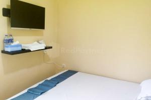 1 dormitorio con 1 cama y TV en la pared en Arwana Inn Lampung RedPartner en Bandar Lampung
