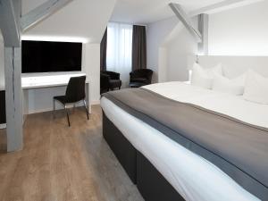 a hotel room with a large bed and a desk at DORMERO Hotel Worms in Worms