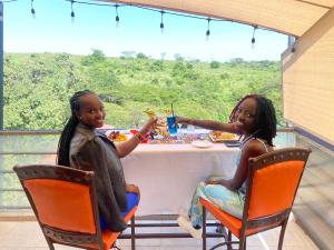 dos jovencitas sentadas en una mesa comiendo comida en Olsupat Lodge, en Nairobi
