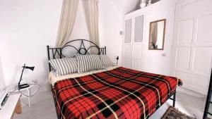 una camera con un letto con una coperta rossa e nera di Dar Essarouel Hammamet a Hammamet