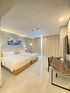 1 dormitorio con 2 camas, mesa y TV en THE 1O1 Malang OJ, en Malang