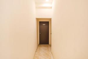 un pasillo con una puerta negra y una pared blanca en FabHotel Seva Service Apartment, en Nagpur