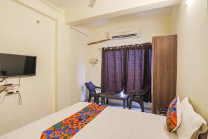 1 dormitorio con 1 cama, TV y silla en FabHotel Seva Service Apartment, en Nagpur