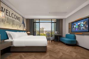 ein Hotelzimmer mit einem Bett und einem Flachbild-TV in der Unterkunft Mehood Hotel Huangshan High-Speed North Station in Huangshan