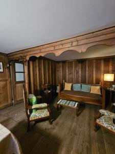 a bedroom with wooden walls and a bed and two chairs at L'Atelier du Temps - Casa Ronc in Etroubles