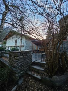 a building with a stone wall and a tree at L'Atelier du Temps - Casa Ronc in Etroubles