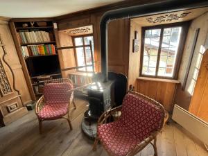 a living room with two chairs and a stove at L'Atelier du Temps - Casa Ronc in Etroubles