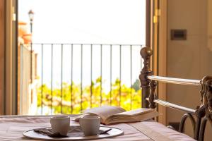 un plato con dos tazas y un libro sobre una mesa en A casa dù Rumanu - Taormina, en Castelmola