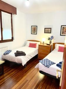 two beds in a room with wooden floors at Mundaka bihotzean con parking gratuito in Mundaka