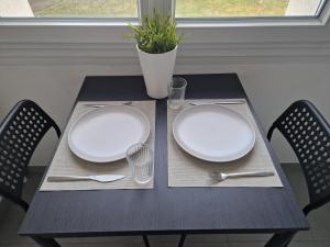 a black table with two plates and silverware on it at Studio confort in Fleury-les-Aubrais +7 photos