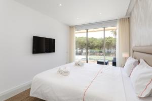 a bedroom with a large white bed with a tv at Hopstays - Vila das Lagoas - Salgados in Albufeira +20 photos