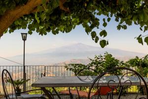 una mesa y sillas con vistas a la montaña en A casa dù Rumanu - Taormina, en Castelmola