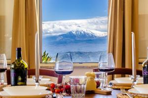 una mesa con copas de vino y vistas a la montaña en A casa dù Rumanu - Taormina, en Castelmola