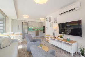 a living room with a couch and chairs and a tv at Marina Apartman Balatonszemes by BLTN in Balatonszemes