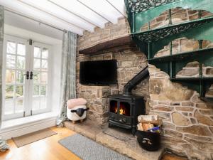 a stone fireplace in a living room with a stove at Bear Pit Cottage in Hayfield