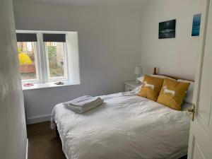 a bedroom with a bed with yellow pillows and a window at Bear Pit Cottage in Hayfield