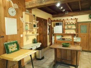 une cuisine avec des murs en bois, une table et une horloge dans l'établissement Gites Des Esselards, à Yzeron