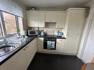 a kitchen with white cabinets and a sink at 2-Bed Apartment in Coleshill in Birmingham
