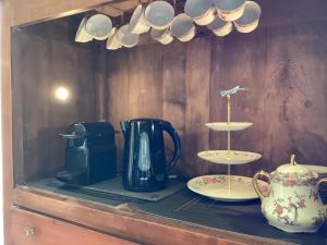 un estante con una cafetera y tazas y platos en Le clos de l’Âne Dentelle, en Vézac
