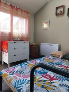 a bedroom with a bed and a dresser and a window at le prieuré reposant in Notre-Dame de la Mer