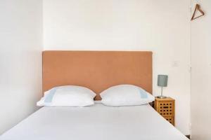 a bed with two white pillows and a brown headboard at Chambres privées, au cœur des sites olympiques in Saint-Denis