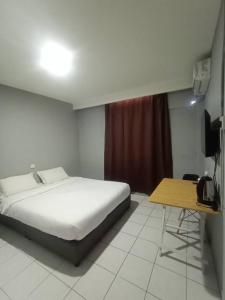a bedroom with a bed and a table and a television at Hotel Iramanis in Lahad Datu